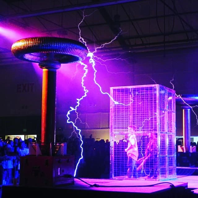 a group of people standing in front of a cage with a lightning bolt